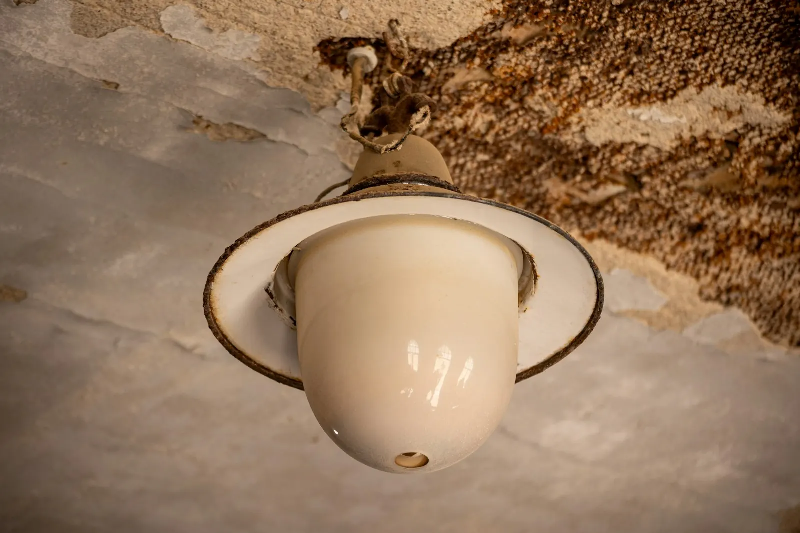 Ceiling light fixture surrounded by water-stained, damaged ceiling