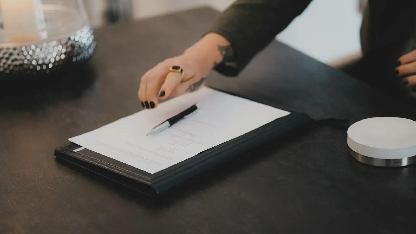 Person signing a document on a clipboard at a table