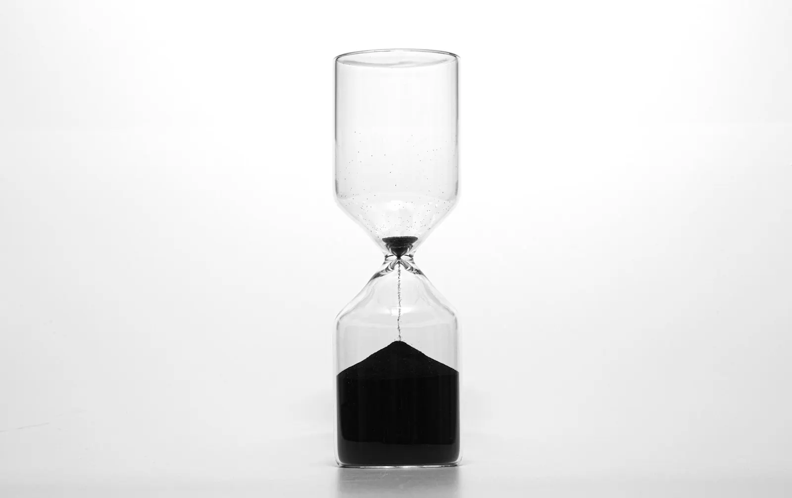 Hourglass with sand running out against a white background