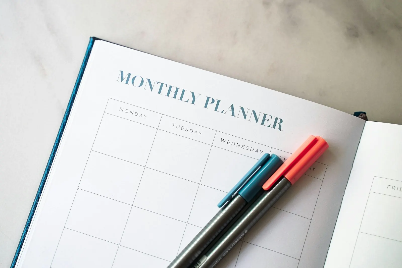 Open monthly planner with two pens, used for tracking claim deadlines