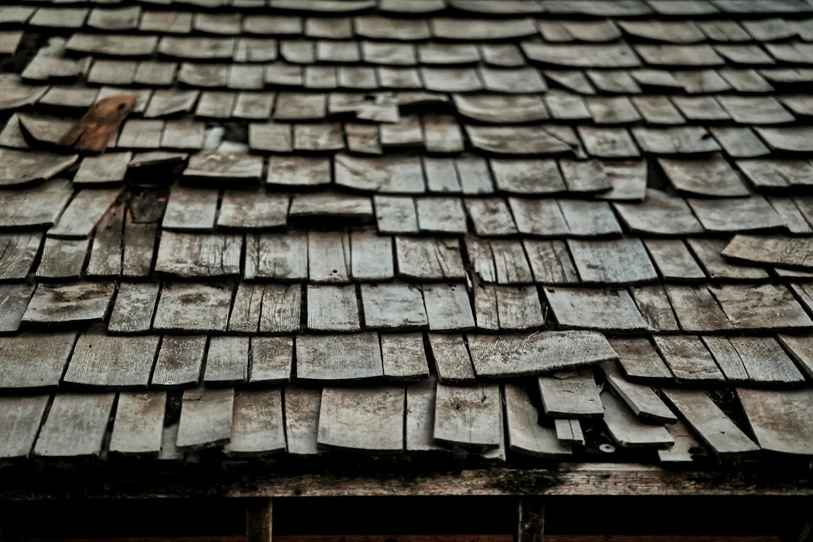 Close-up of old, curling and missing roof shingles showing age-related wear