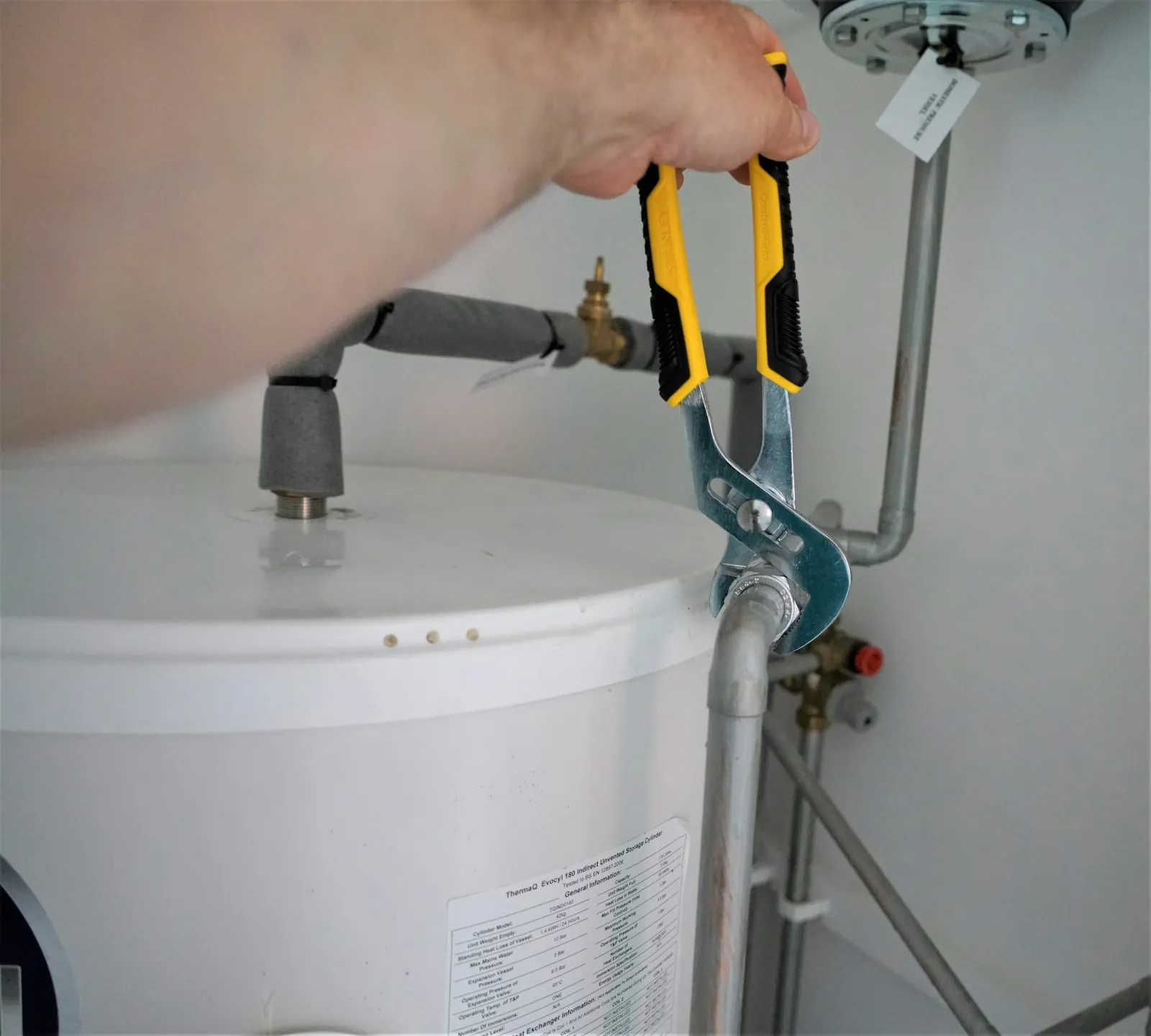 Plumber's pliers tightening a fitting on a residential water heater